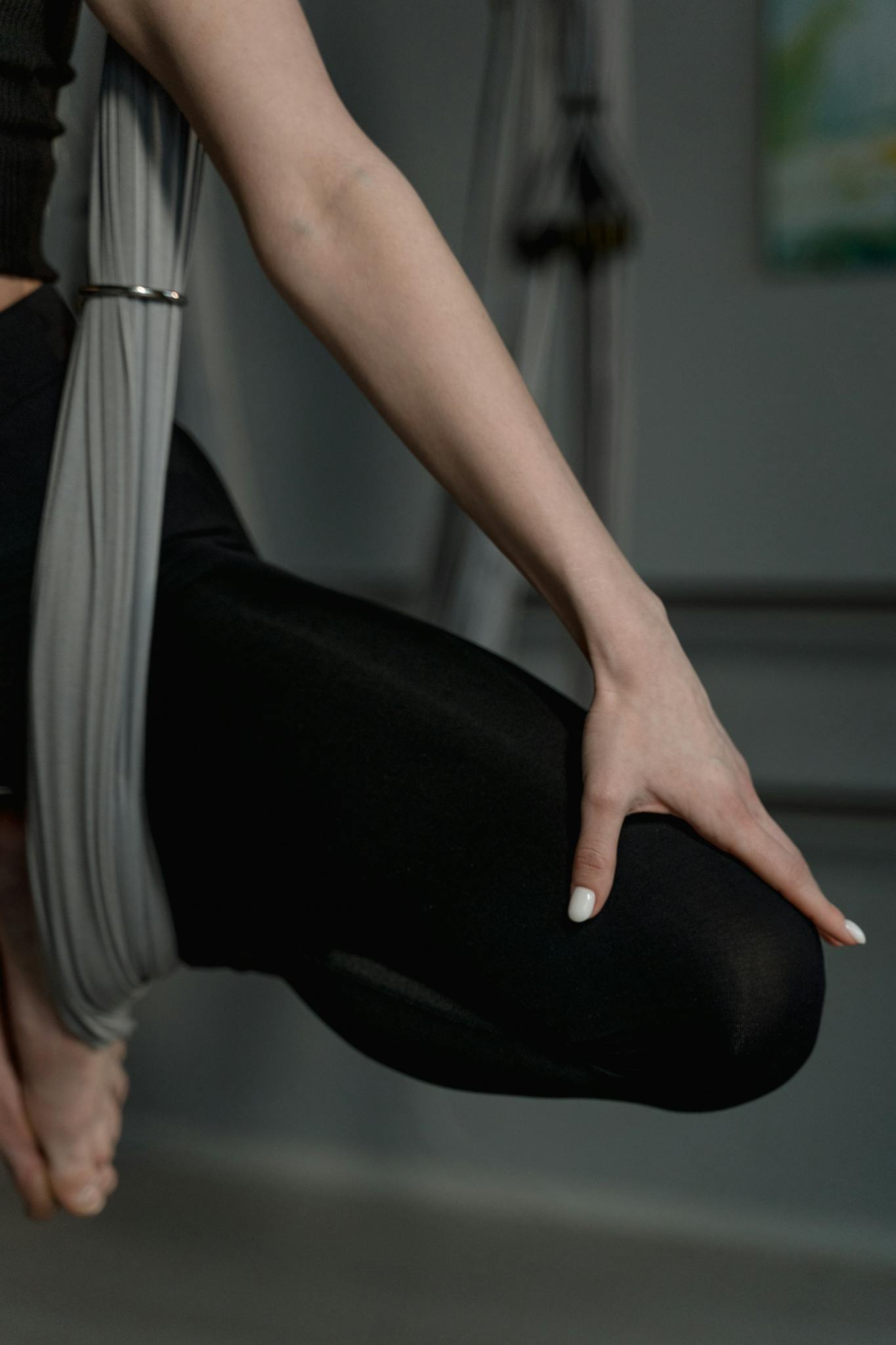 Close-up of person practicing aerial yoga with fabric support in a studio.