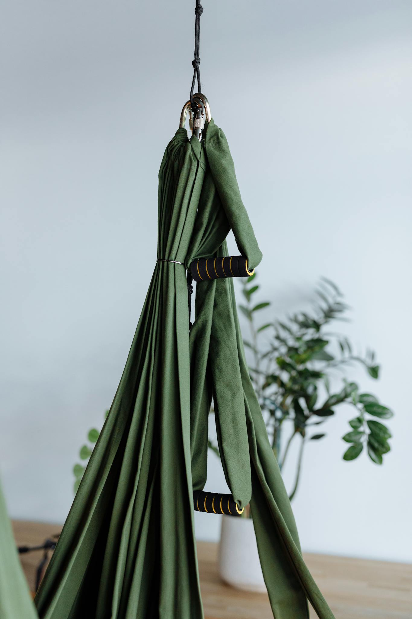 Green aerial yoga fabric hanging in a modern studio with minimalistic decor.